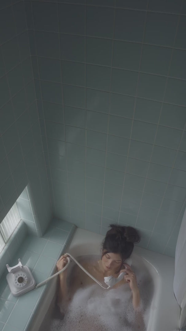 woman talking on a rotary phone in a bubble bath